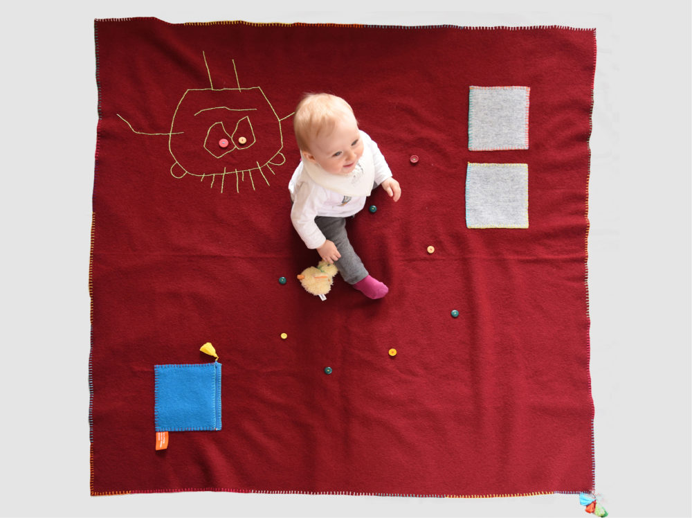 Baby sitzt auf Babywalkdecke